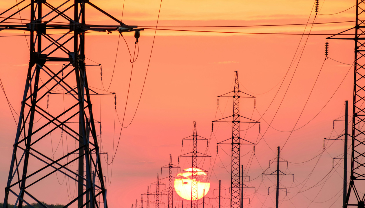 Silhouetted electricity pylons and towers against a vibrant sunset sky, showcasing the beauty of energy infrastructure.